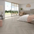 Versat Ash 9x48 Wood Look Porcelain Tile by STN Cerámica featuring light ash-gray wood grain flooring installed in a modern bedroom with natural light and contemporary decor.