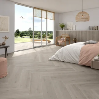 Versat Ash 9x48 Wood Look Porcelain Tile by STN Cerámica featuring light ash-gray wood grain flooring installed in a modern bedroom with natural light and contemporary decor.